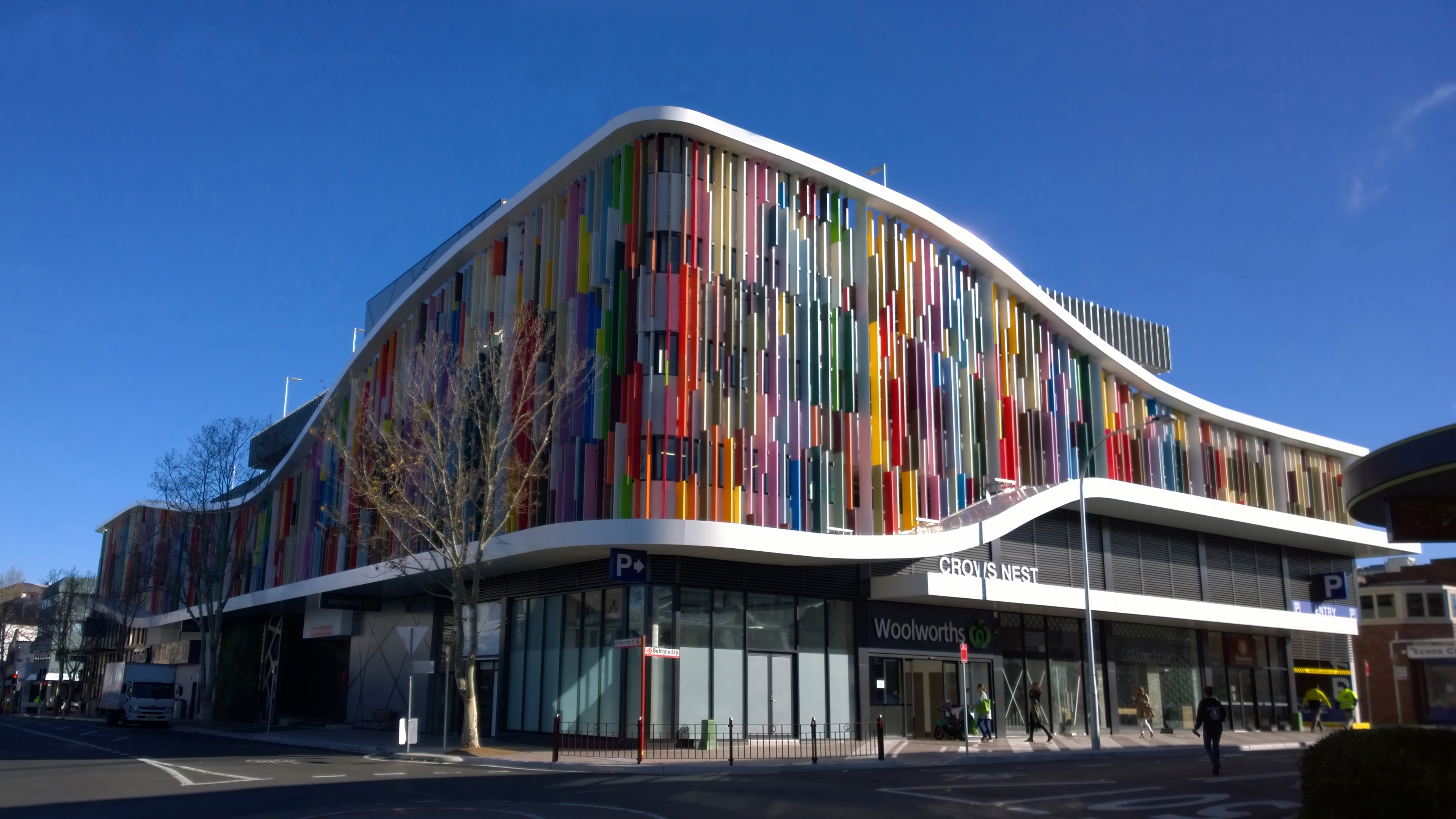 Woolworths supermarket with colorful vertical sun louvers across its curved facade
