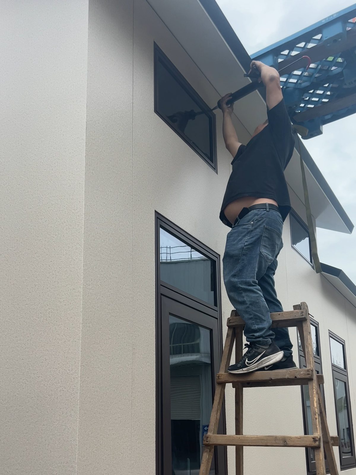 Worker on a ladder finishing the roof edge and ceiling line