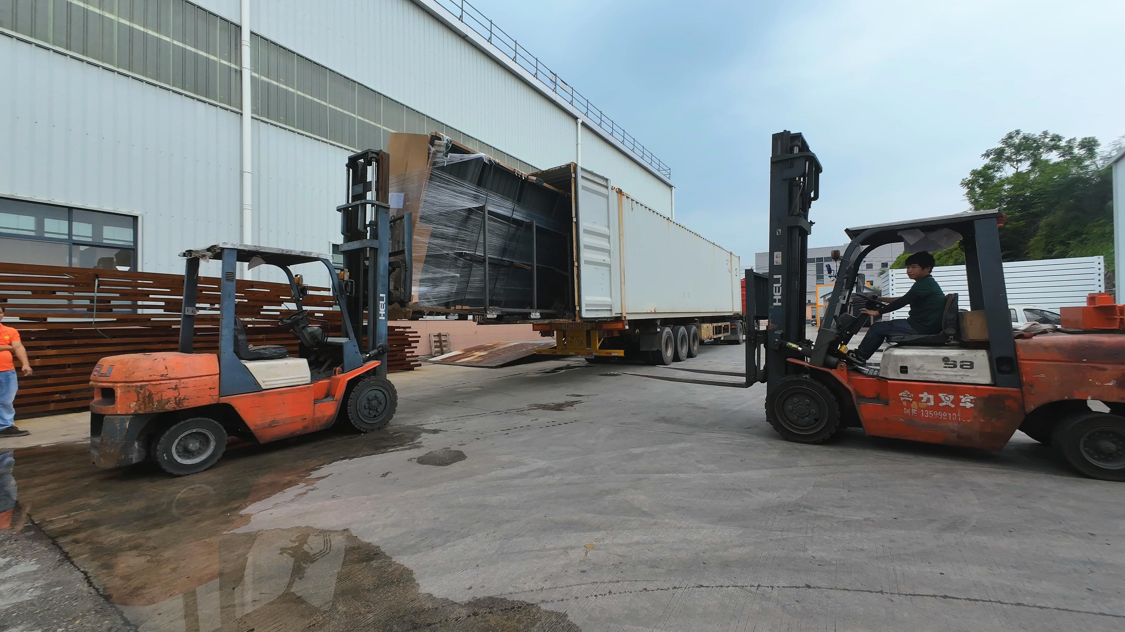 Forklifts loading a protected building component into a shipping container